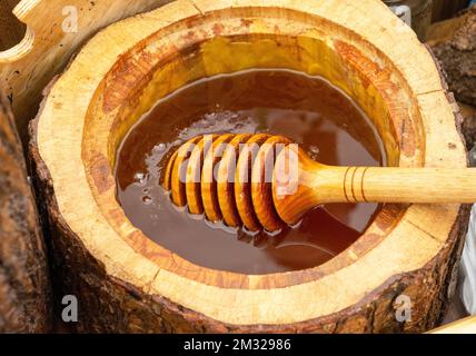 Honey spoon buried in a barrel of fragrant fresh honey. Close-up, healthy eating concept. Stock Photo