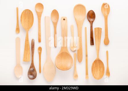 set of empty wooden spoons of different sizes with over white background, trendy flat lay Stock Photo