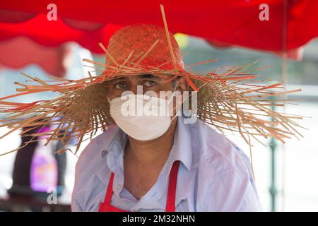 Illustration picture shows a fruits and vegetable sales man wearing a large straw hat and a mouth mask at the open-air market 'Marche de la Batte', Belgium's biggest market, in Liege, Sunday 24 May 2020. Belgium is in its tenth week of confinement in the ongoing corona virus crisis, different sectors of the public life are gradually reopening. BELGA PHOTO NICOLAS MAETERLINCK Stock Photo