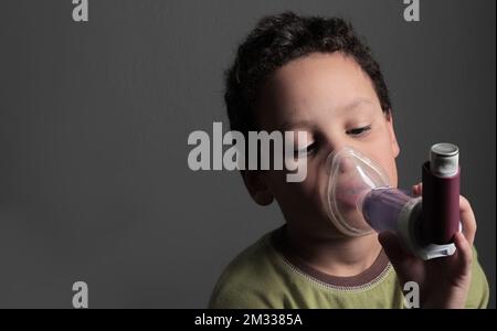 child with flu and inhaler respiratory puff on grey background with ...