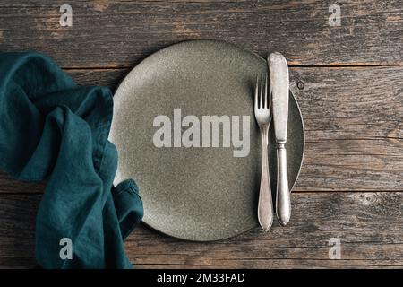Vintage silverware and empty green plate on a wooden table background. Dining table setting. Top view Stock Photo