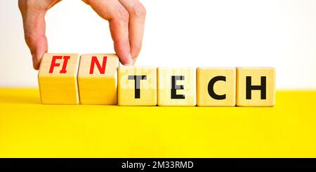 Tech or fintech symbol. Concept word Tech and Fintech on wooden cubes. Businessman hand. Beautiful yellow table white background. Business and tech or Stock Photo