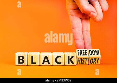 Black history and freedom symbol. Concept words Black history Black freedom on wooden cubes. Businessman hand. Beautiful orange table orange backgroun Stock Photo