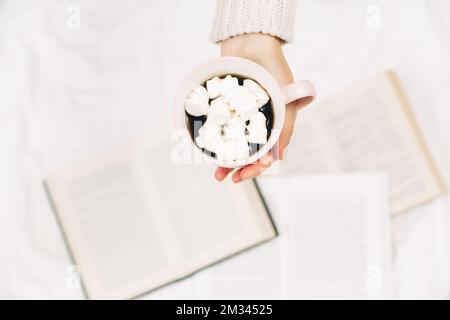 Women hands with cup of coffee and books.Stylish minimalist photo.Top view. Stock Photo
