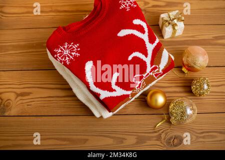 Warm Christmas sweaters. Winter holiday knitted sweaters with pattern on a wooden background with Christmas decorations.Stack of warm Christmas Stock Photo