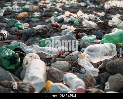 Stone beach with plastic waste. Plastic bottles in nature. Environmental pollution concept. Stock Photo