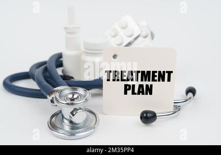 Medical concept. On a white surface, medicines, a stethoscope and writing paper with the text - TREATMENT PLAN Stock Photo
