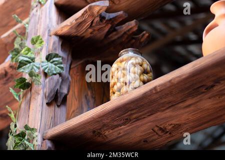 pickled garlic in a large glass jar on a wooden shelf. Tasty pickled garlic Stock Photo
