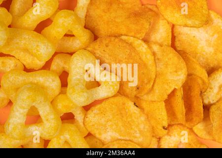Crispy potato and corn chips, close-up view from above. Stock Photo