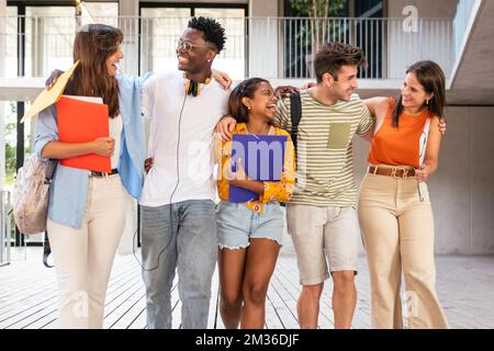 Cheerful students walking together in the campus. Group of international students laughing together at the university Stock Photo