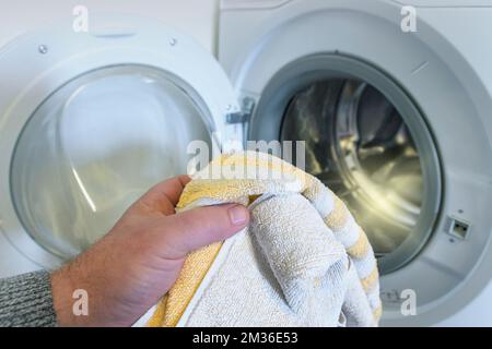 washing light-colored clothes in the washing machine. man holding a towel Stock Photo