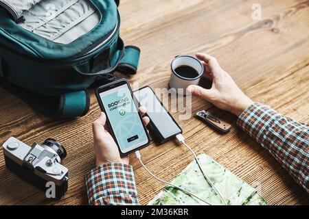 Man planning next vacation trip. Booking hotel online using smartphone. Ordering service. Charging mobile phone with power bank. Using technology whil Stock Photo
