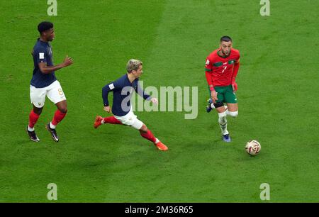 Morocco’s Hakim Ziyech (right) is pursued by France’s Antoine Griezmann and France’s Aurelien Tchouameni during the FIFA World Cup Semi-Final match at the Al Bayt Stadium in Al Khor, Qatar. Picture date: Wednesday December 14, 2022. Stock Photo