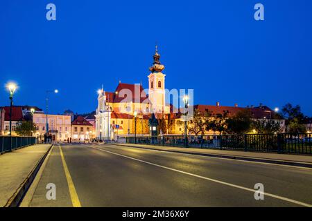 Gyor, city in Hungary,  baroque Carmelite church by night  from bridge over Raba river Stock Photo