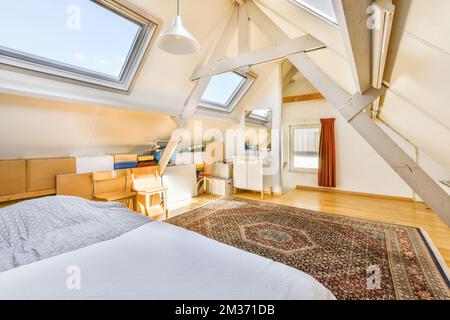 a bed in a room with skylights on the ceiling and an area rug under it that has been used for several years Stock Photo
