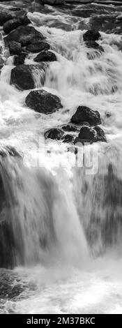A vertical black-and-white shot of a small waterfall in Yellowstone, Wyoming Stock Photo