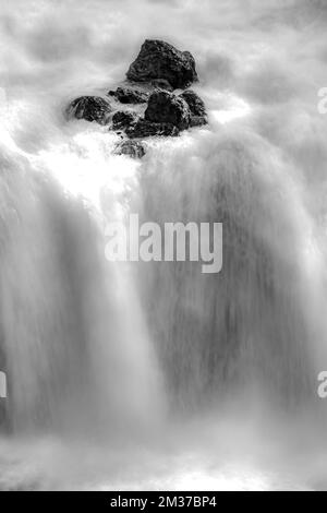 A vertical black and white shot of a small waterfalls in Yellowstone, Wyoming Stock Photo