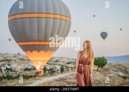 Tourist woman looking at hot air balloons in Cappadocia, Turkey. Happy Travel in Turkey concept. Woman on a mountain top enjoying wonderful view Stock Photo
