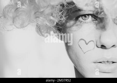 Girl dressed as an angel with wings and curly hair on an isolated ...