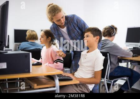 Teacher helping student with computer work Stock Photo