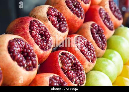 Open pomegranates apples oranges at street market. Fruits counter fresh juice. Stock Photo