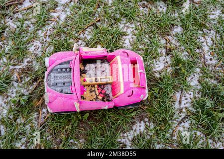 Pink retro convertible plastic toy car for 18-inch dolls by Og Girl dumped in a field on a cold, frosty day. Stock Photo