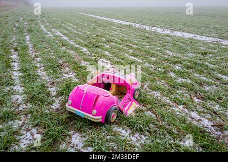 Pink retro convertible plastic toy car for 18-inch dolls by Og Girl dumped in a field on a cold, frosty day. Stock Photo