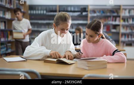 Girls doing homework together in library Stock Photo