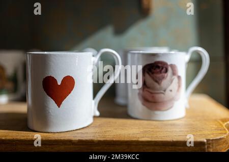 London, UK - 15 November 2022 White porcelain mugs and saucers with a red heart print. Liberty shop. Stock Photo