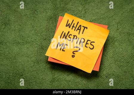 What inspires me? Handwritten question on a sticky note. Inspiration and personal development concept. Stock Photo