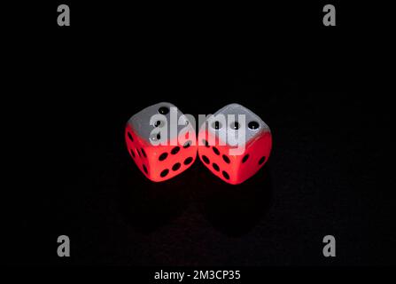 Old white dices with double three and six pair iluminated with red and white lights over a black background Stock Photo