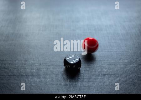 Closeup to a dices, one dice is red and one black dice is spinning over a black background. Ideal for gamble, board games and bets Stock Photo
