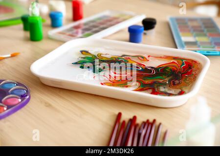 Container with water and paints for Ebru on table in workshop, closeup Stock Photo