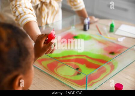 Little girl and teacher with paints in workshop for Ebru painting, closeup Stock Photo