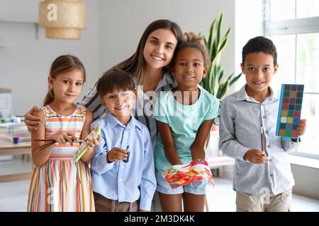 Female teacher, little children with paints, brushes and painting in workshop for Ebru Stock Photo