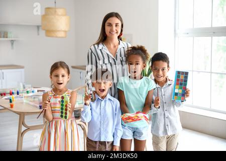 Female teacher, little children with paints, brushes and painting in workshop for Ebru Stock Photo