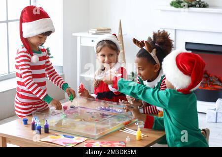 Little children in Christmas costumes pouring paints into water at workshop for Ebru painting Stock Photo