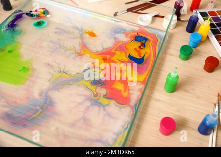 Container with water and paints for Ebru on table in workshop, closeup Stock Photo