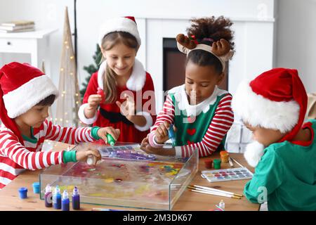 Little children in Christmas costumes pouring paints into water at workshop for Ebru painting Stock Photo