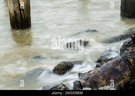 ghostly swirling waves breaking on rocks Stock Photo