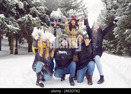 Portrait of group of happy men and women having fun and playing with snow in winter forest. Stock Photo