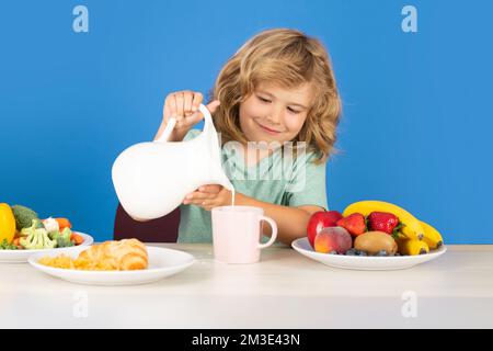 Healthy child pours milk from jug. Child drink dairy milk. Stock Photo