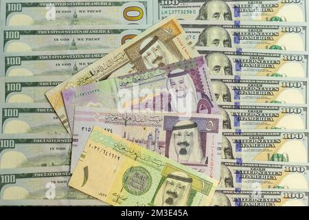 Saudi Arabia riyal banknotes over a US 100 dollar bills closeup Stock Photo