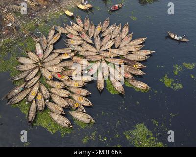 Dhaka, Bangladesh. 15th Dec, 2022. A fleet of wooden boats fans out around their moorings in the Buriganga River in Dhaka, Bangladesh. The river is widely used to transport goods, produce, and people. An estimated 50,000 commuters cross the Buriganga from Keraniganj to work in Dhaka, and many take boats. Hundreds of small boats, called 'Dinghy Noukas', are moored in the river port of Dhaka, the capital of Bangladesh. In them, ferrymen transport workers, goods, and tourists across the Buriganga River every day. Credit: Joy Saha/Alamy Live News Stock Photo