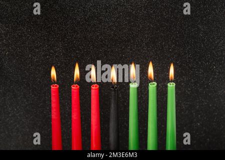 Kwanzaa festival concept with seven candles red, black and green on black background, copy space Stock Photo