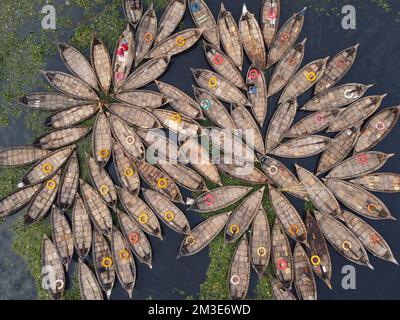 Dhaka, Bangladesh. 15th Dec, 2022. A fleet of wooden boats fans out around their moorings in the Buriganga River in Dhaka, Bangladesh. The river is widely used to transport goods, produce, and people. An estimated 50,000 commuters cross the Buriganga from Keraniganj to work in Dhaka, and many take boats. Hundreds of small boats, called 'Dinghy Noukas', are moored in the river port of Dhaka, the capital of Bangladesh. In them, ferrymen transport workers, goods, and tourists across the Buriganga River every day. Credit: Joy Saha/Alamy Live News Stock Photo