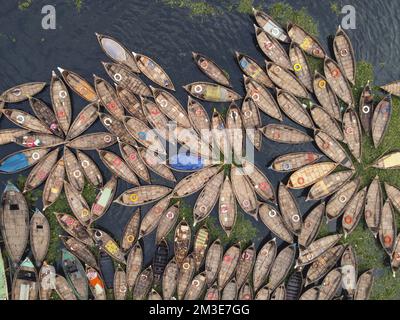 Dhaka, Bangladesh. 15th Dec, 2022. A fleet of wooden boats fans out around their moorings in the Buriganga River in Dhaka, Bangladesh. The river is widely used to transport goods, produce, and people. An estimated 50,000 commuters cross the Buriganga from Keraniganj to work in Dhaka, and many take boats. Hundreds of small boats, called 'Dinghy Noukas', are moored in the river port of Dhaka, the capital of Bangladesh. In them, ferrymen transport workers, goods, and tourists across the Buriganga River every day. Credit: Joy Saha/Alamy Live News Stock Photo