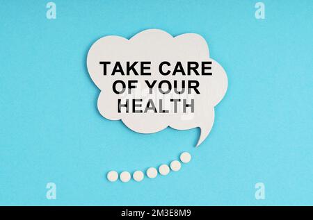 Medicine and health concept. On a blue table are pills and a white plate with the inscription - Take care of your health Stock Photo