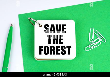 Ecology and industry concept. On a white surface lies a green sheet of paper, a pen and a notebook with the inscription - Stock Photo