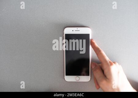 Close up of woman hand using smartphone isolated on orange wall. Female hands showing empty white screen of modern smart phone. Businesswoman holding Stock Photo